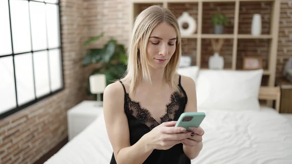 年轻的金发女人在床上用智能手机 — 图库照片