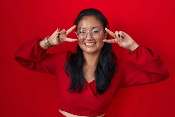 Aziatisch Jong Vrouw Staande Rode Achtergrond Doen Vrede Symbool Met — Stockfoto