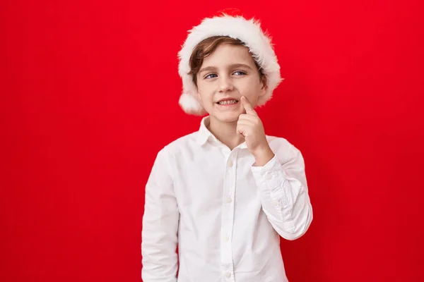 Niño Caucásico Con Sombrero Navidad Sobre Fondo Rojo Sonriente Mirando —  Fotos de Stock