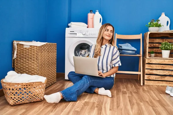 Young Blonde Woman Using Laptop Waiting Washing Machine Laundry Room — стоковое фото