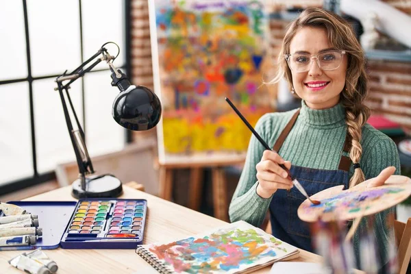 在艺术工作室的桌子上 年轻的女画家坐在笔记本上画画 — 图库照片