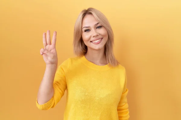 Sarı Kazak Giyen Genç Beyaz Kadın Numarayı Gösterip Işaret Ederken — Stok fotoğraf