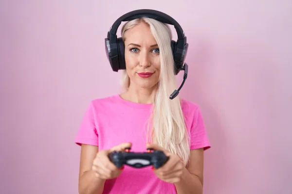 本格的な表情でリラックスしたコントローラーを手にビデオゲームをプレイしている白人女性 カメラを見ているだけで — ストック写真