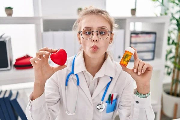 Jovem Médico Caucasiano Mulher Segurando Pílulas Coração Fazendo Cara Peixe — Fotografia de Stock
