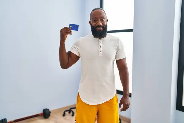 Hombre Afroamericano Usando Ropa Deportiva Sosteniendo Tarjeta Crédito Mirando Positiva —  Fotos de Stock