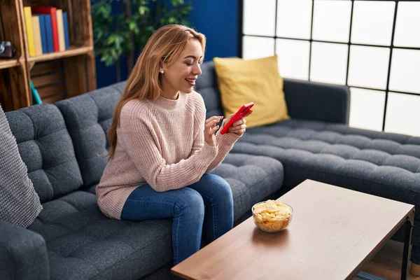 Young Woman Using Smartphone Eating Chips Potatoes Home — Stock Photo, Image