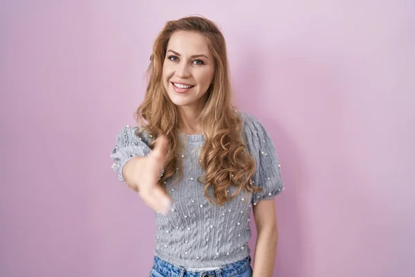Beautiful Blonde Woman Standing Pink Background Smiling Friendly Offering Handshake — Stock Photo, Image