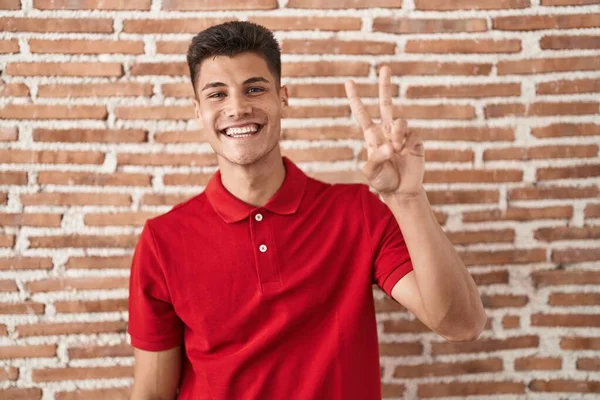 Joven Hombre Hispano Pie Sobre Pared Ladrillos Sonriendo Mirando Cámara — Foto de Stock