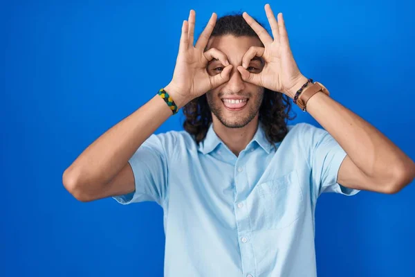 Young Hispanic Man Standing Blue Background Doing Gesture Binoculars Sticking — Stock Photo, Image