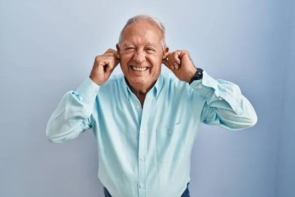 Starší Muž Šedivými Vlasy Stojící Nad Modrým Pozadím Zakrývající Uši — Stock fotografie