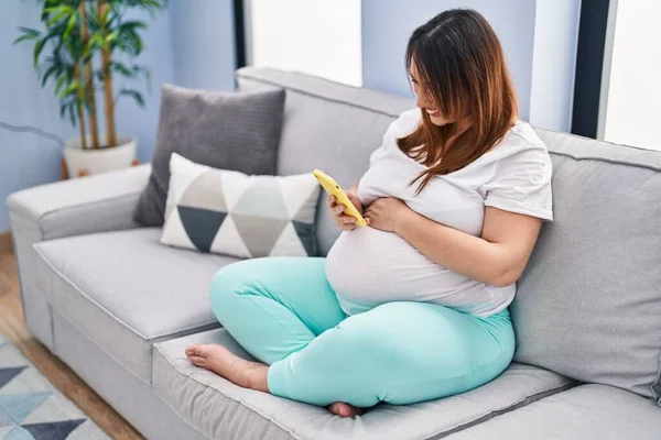 Mladá Těhotná Žena Pomocí Smartphone Sedí Pohovce Doma — Stock fotografie