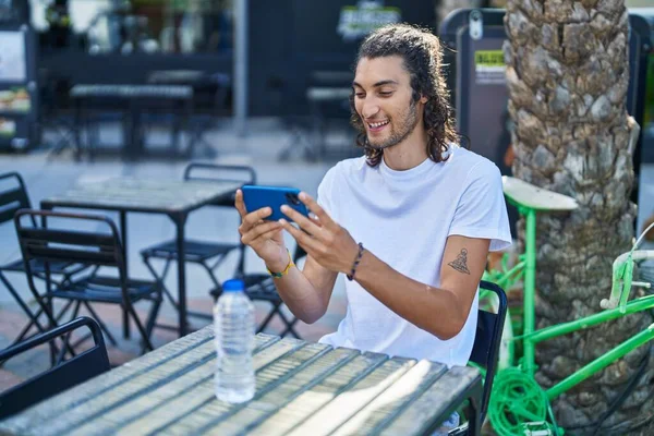 Νεαρός Ισπανόφωνος Βλέποντας Βίντεο Στο Smartphone Κάθεται Στο Τραπέζι Στη — Φωτογραφία Αρχείου