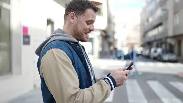 Young Caucasian Man Smiling Using Smartphone Street — Stockfoto