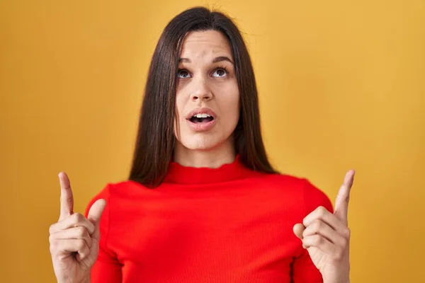 Young Hispanic Woman Standing Yellow Background Amazed Surprised Looking Pointing — Stock Photo, Image