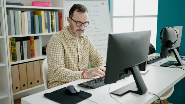 Middle age man teacher using computer working at classroom
