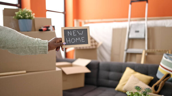 African woman with braided hair holding blackboard at new home