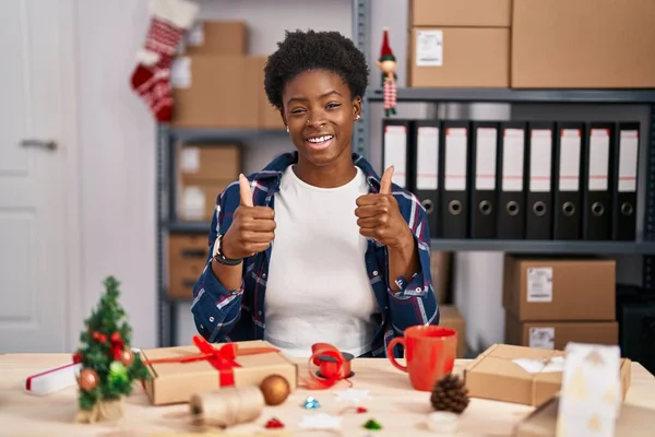 African american woman working at small business doing christmas decoration success sign doing positive gesture with hand, thumbs up smiling and happy. cheerful expression and winner gesture.