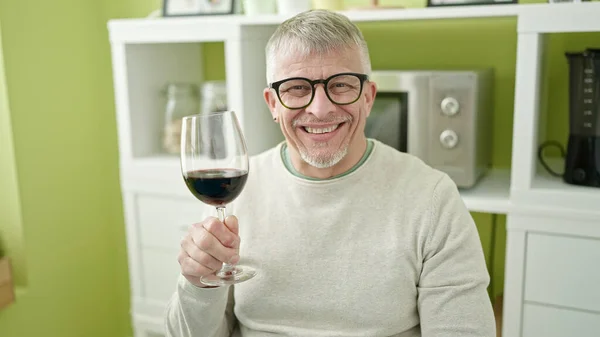 Siwy Mężczyzna Średnim Wieku Pijący Kieliszek Wina Siedzący Stole Domu — Zdjęcie stockowe