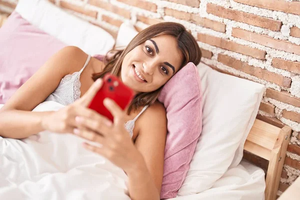 Νεαρή Όμορφη Ισπανόφωνη Γυναίκα Που Χρησιμοποιεί Smartphone Ξαπλωμένη Στο Κρεβάτι — Φωτογραφία Αρχείου