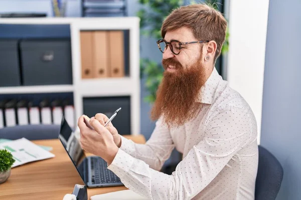 Young Redhead Man Business Worker Using Laptop Writing Reminder Paper — Φωτογραφία Αρχείου