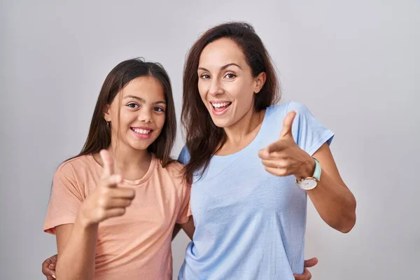 stock image Young mother and daughter standing over white background pointing fingers to camera with happy and funny face. good energy and vibes. 