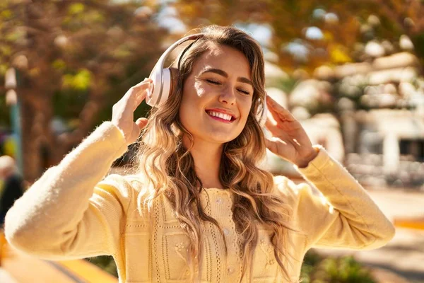 公園で音楽を聞いて自信を持って笑っている若い女性 — ストック写真