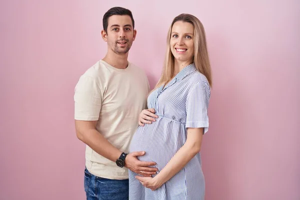 Casal Jovem Esperando Bebê Sobre Fundo Rosa Com Sorriso Feliz — Fotografia de Stock