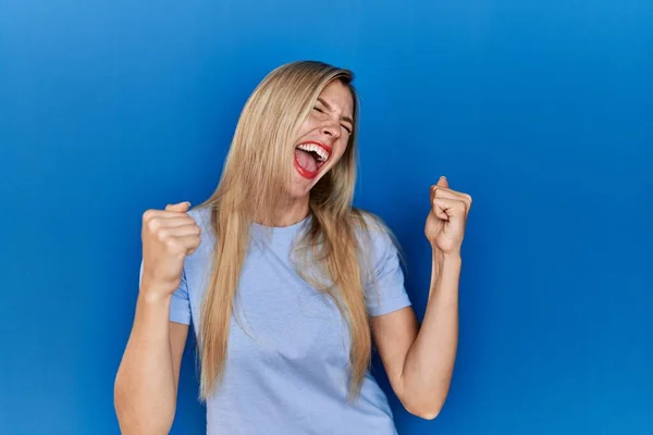 Mooie Blonde Vrouw Dragen Casual Shirt Blauwe Achtergrond Erg Blij — Stockfoto