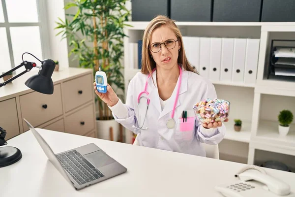 Ung Blond Läkare Kvinna Som Håller Glukometer Och Sötsaker Chockansikte — Stockfoto