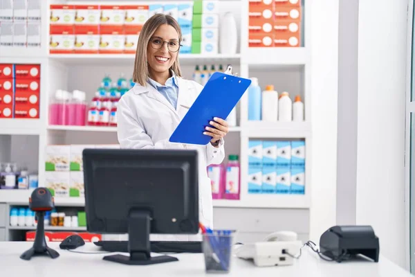 Young Beautiful Hispanic Woman Pharmacist Reading Document Using Computer Pharmacy — Fotografia de Stock