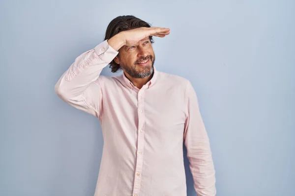 ハンサムな中年の男性がエレガントなシャツの背景を着て非常に幸せと笑みを浮かべて遠くに手を頭の上に見て 検索の概念 — ストック写真