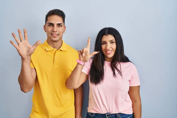 Young Couple Standing Isolated Background Showing Pointing Fingers Number Seven — Stock Photo, Image