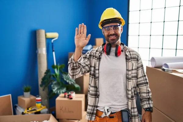 髭を生やした若いヒスパニック系の男が家の改装で働いているこんにちは幸せと笑顔 優しい歓迎のジェスチャー — ストック写真