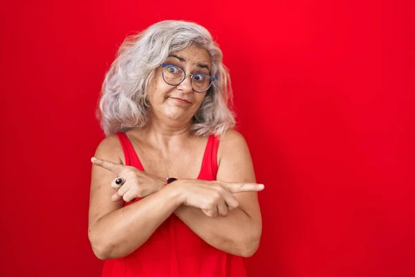 Kırmızı Arka Planda Duran Gri Saçlı Orta Yaşlı Kadın Parmaklarıyla — Stok fotoğraf
