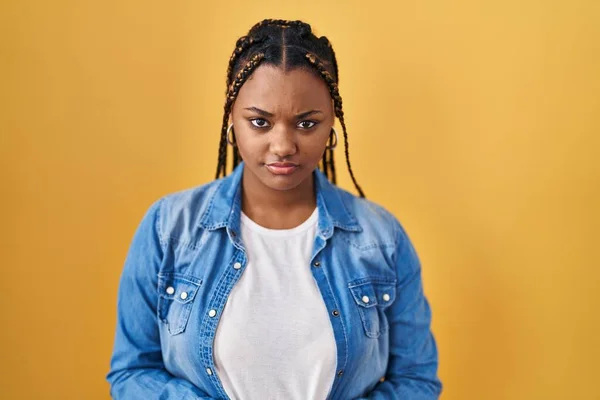 アフリカ系アメリカ人の女性は 黄色の背景の懐疑的で緊張して立っており 問題のために動揺して眉をひそめています 否定的な人 — ストック写真