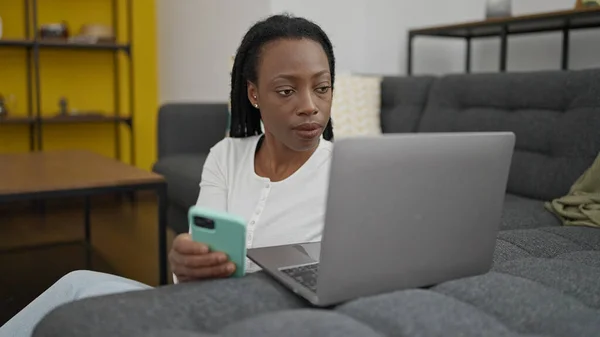 Afroamerykanka Pomocą Smartfona Laptopa Siedzi Podłodze Domu — Zdjęcie stockowe
