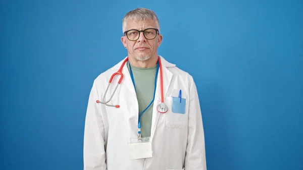 中年白髪の男医師立ちますとともにリラックスした式上の隔離された青の背景 — ストック写真