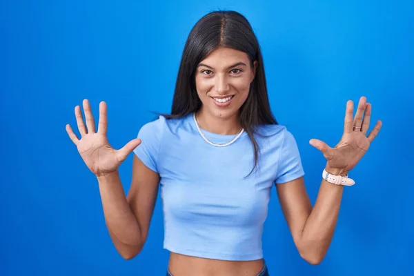 Esmer Genç Bir Kadın Mavi Arka Planda Duruyor Parmaklarını Numarayı — Stok fotoğraf