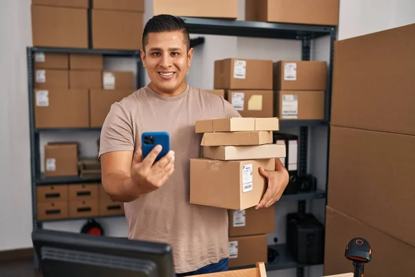 Młody Latynos Człowiek Commerce Pracownik Pomocą Smartfona Gospodarstwa Pakiety Biurze — Zdjęcie stockowe