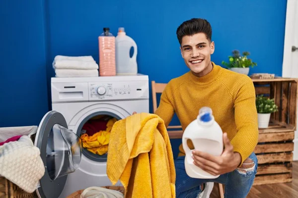 Jovem Hispânico Lavando Roupas Segurando Garrafa Detergente Lavanderia — Fotografia de Stock