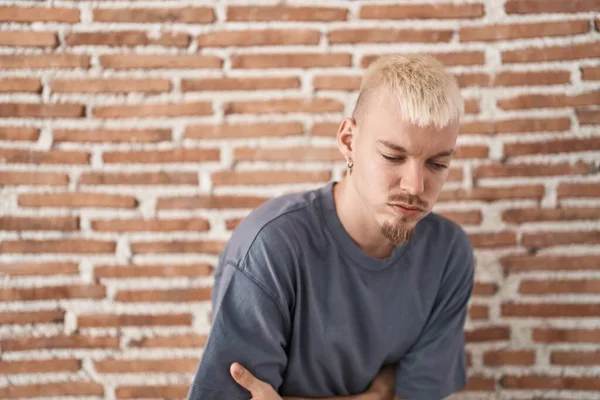 年轻的白人男子站在砖墙上 手放在肚子上 因为消化不良 痛苦不堪 疼痛的概念 — 图库照片