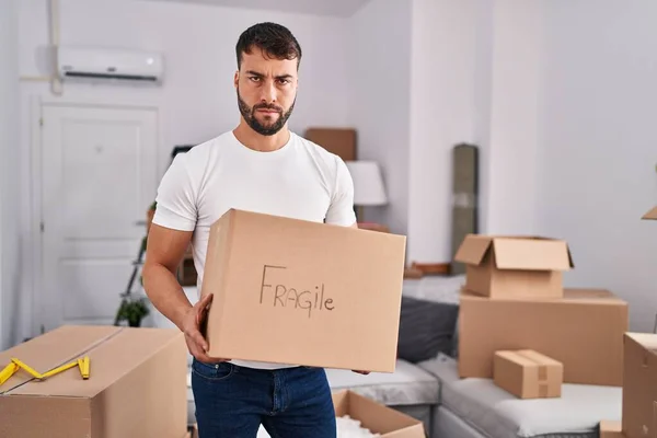 Handsome Hispanic Man Moving New Home Holding Fragile Box Skeptic — Stockfoto