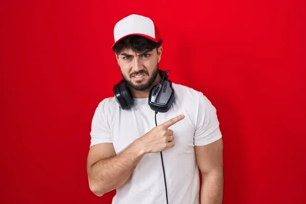 Hispanic Man Beard Wearing Gamer Hat Headphones Pointing Aside Worried — Stock Photo, Image