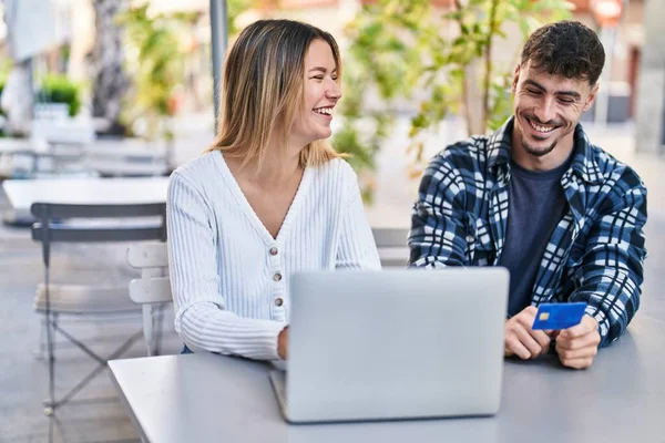 stock image Young man and woman couple using laptop and credit card sitting on table at coffee shop terrace