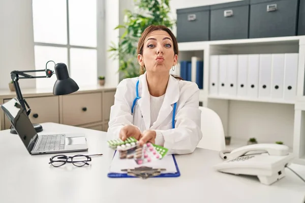 Young Brunette Doctor Woman Holding Pills Looking Camera Blowing Kiss — Stock Photo, Image