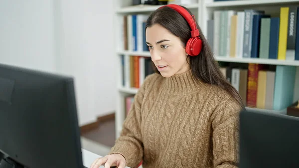 大学の教室でコンピュータとヘッドフォンを使用して若い美しいヒスパニック系女性の学生 — ストック写真