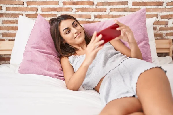 Young Beautiful Hispanic Woman Watching Video Smartphone Lying Bed Bedroom — Stockfoto