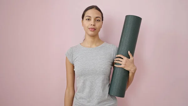 Junge Schöne Hispanische Frau Sportbekleidung Hält Yogamatte Über Isoliertem Rosa — Stockfoto