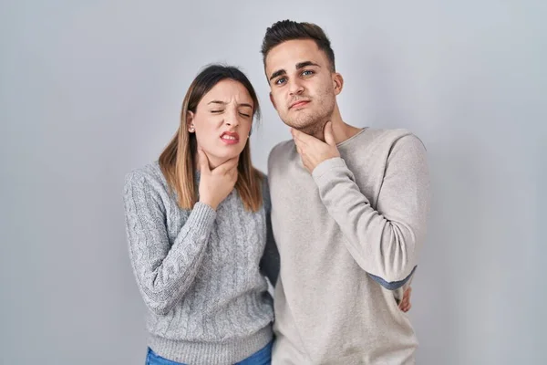 若いですヒスパニック系のカップルは 痛みを伴う首に触れる白い背景の上に立って インフルエンザのための喉の痛み 雲と感染 — ストック写真