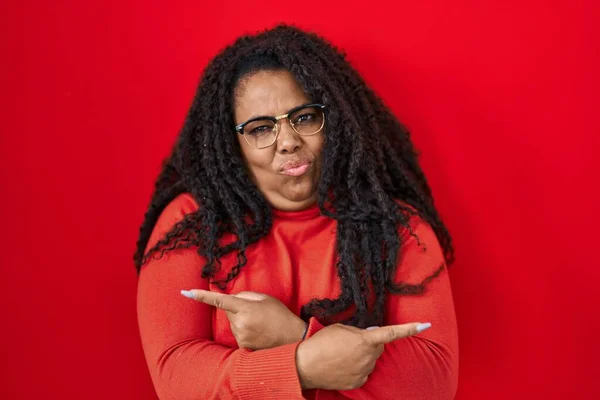 stock image Plus size hispanic woman standing over red background pointing to both sides with fingers, different direction disagree 